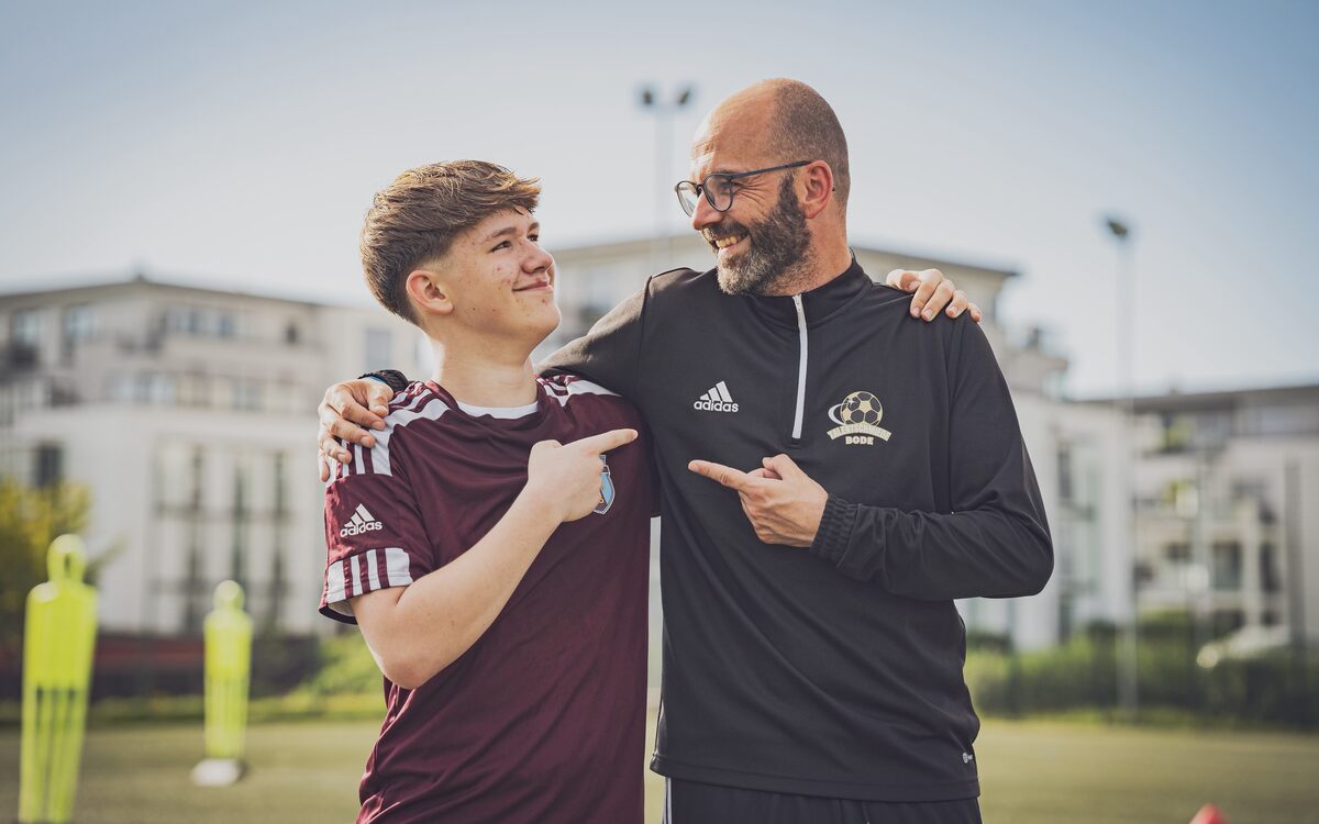 Trainer und Jugendspieler lachen gemeinsam nach der Übung